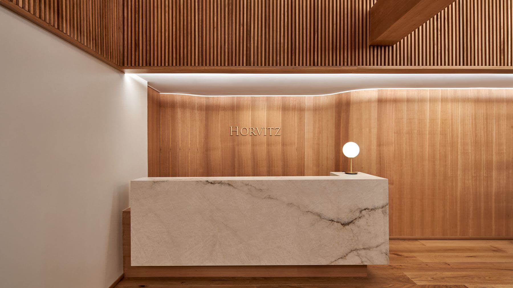 Recepción de oficinas ejecutada por ALMA: revestimiento de madera y mesón de mármol