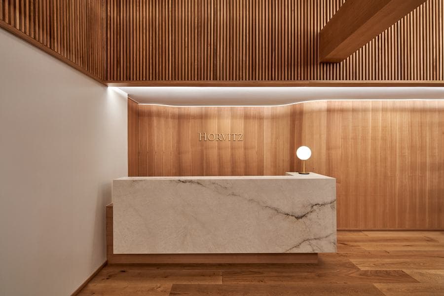 Oficinas Horvitz: recepción con mesón de mármol y revestimiento de madera